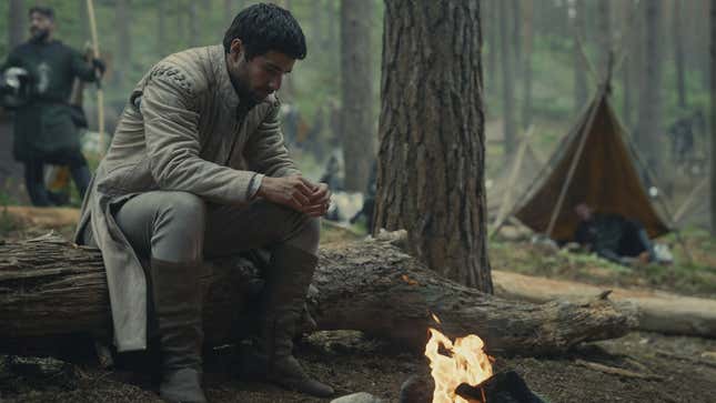 Criston Cole sits next to a fire.